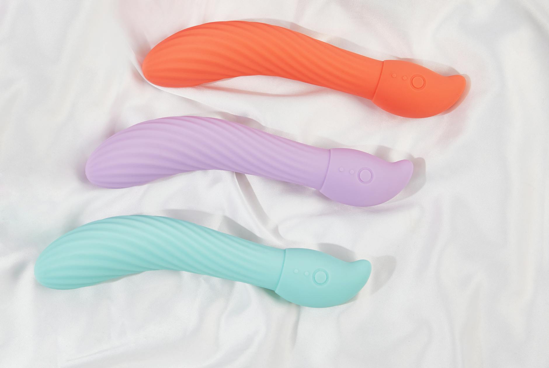 Three colorful lemon clitoral vibrators arranged on white fabric, highlighting their smooth texture