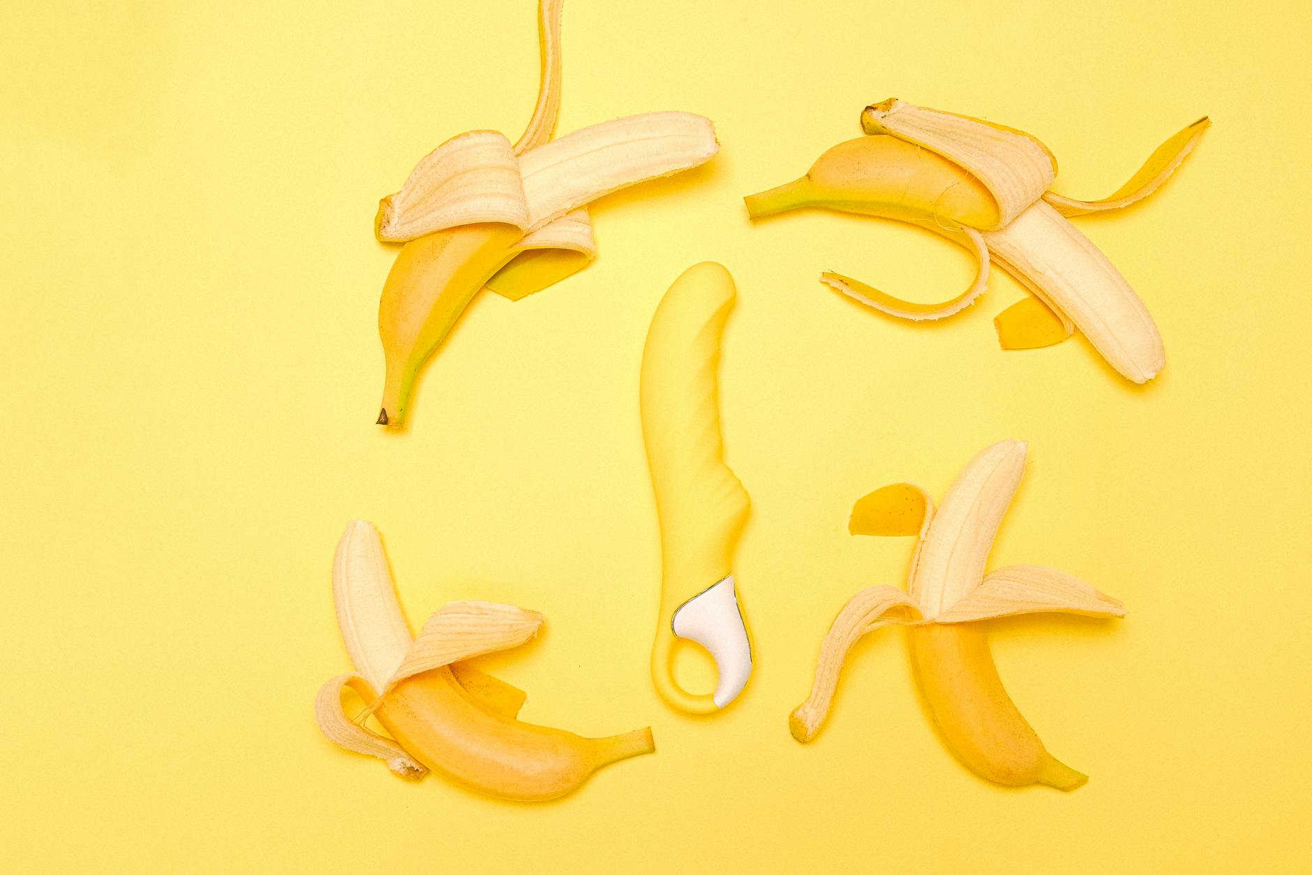A yellow silicone vibrator arranged against a soft, muted background.