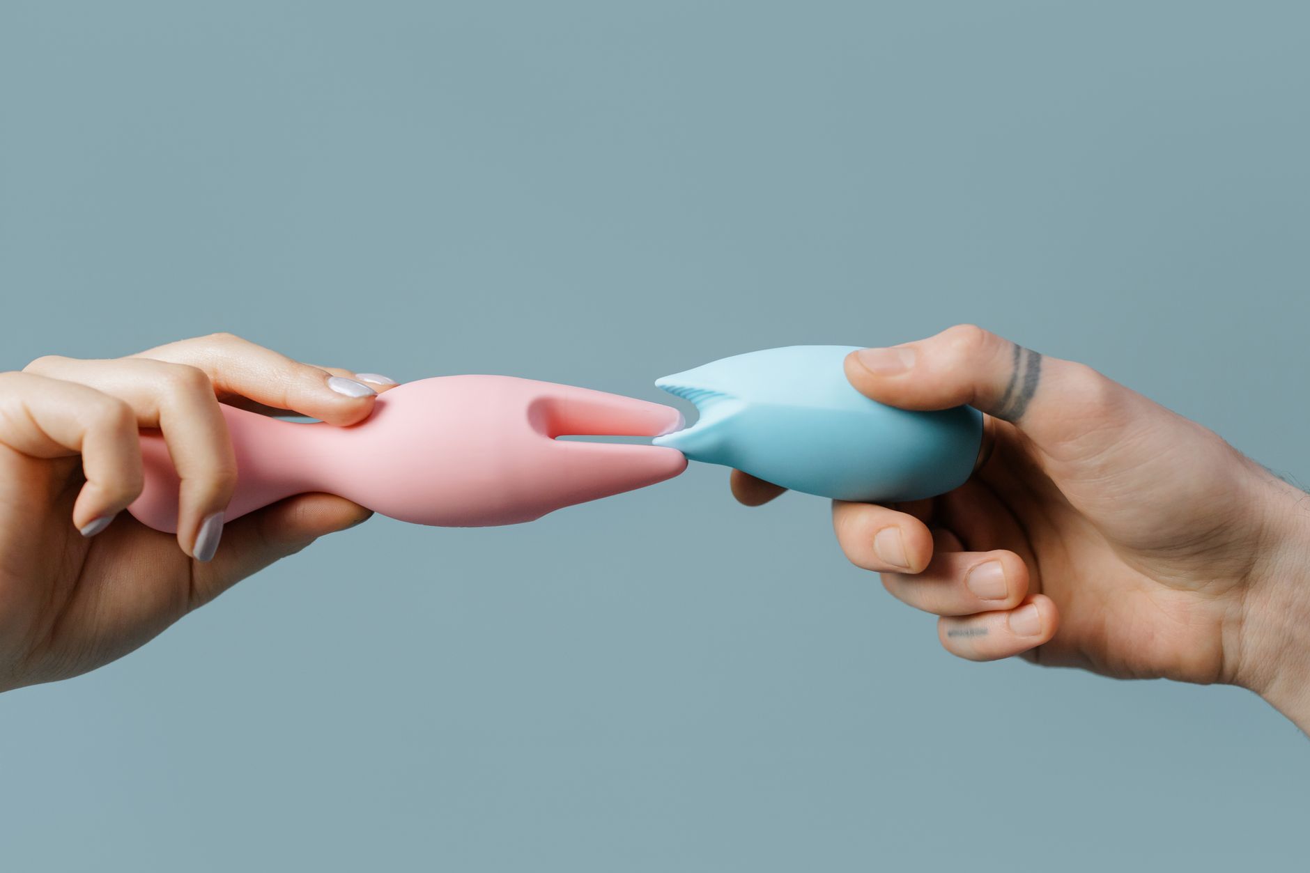 Close-up of hands holding a sleek lemon clitoral vibrator against a soft background